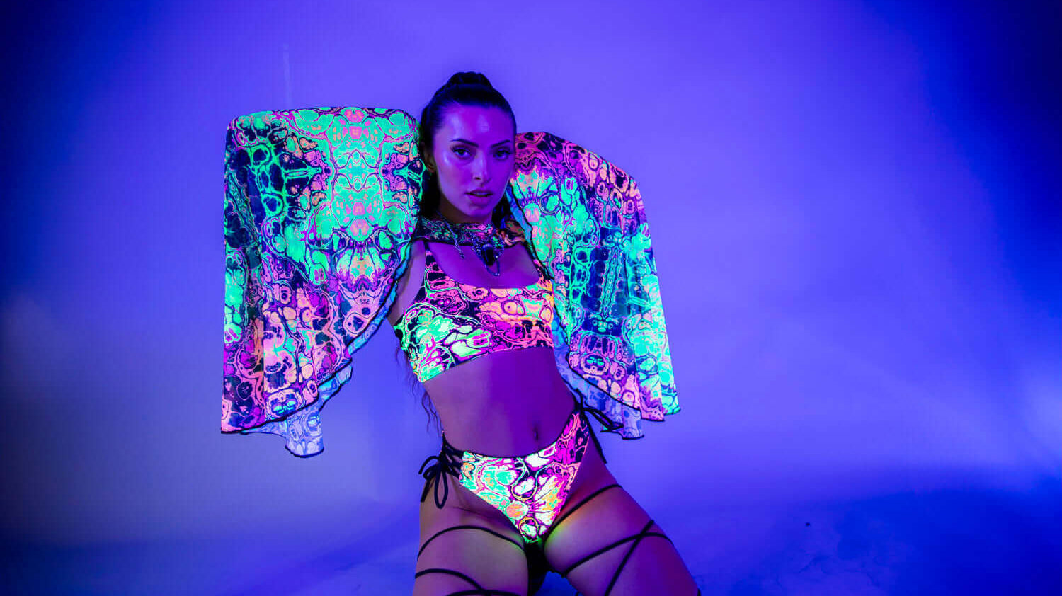 Model in vibrant neon rave outfit with colorful patterns, showcasing neon therapy benefits for mood and confidence.