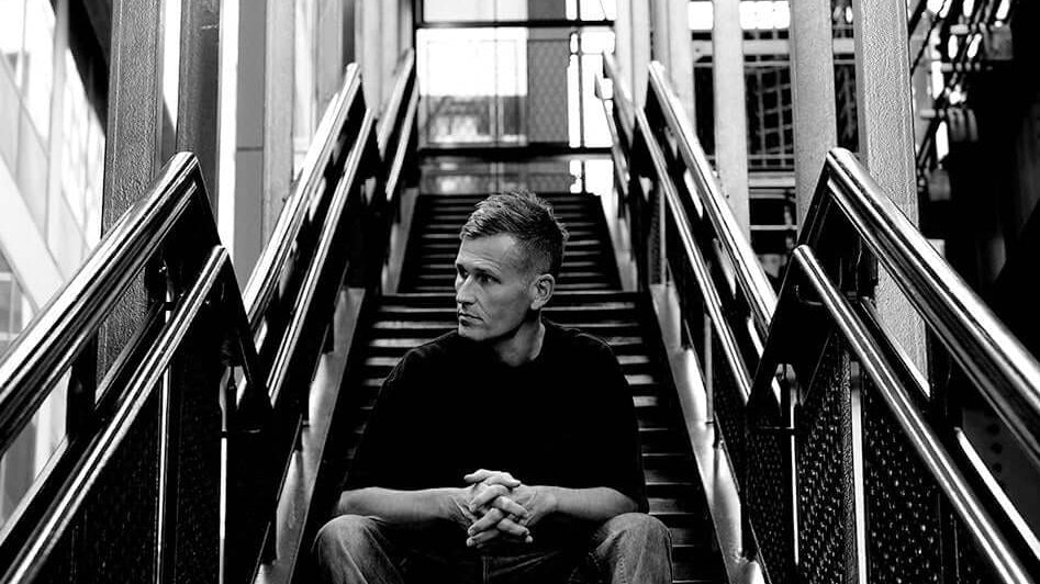 KASKADE ANNOUNCES NEW ALBUM UNDUX. Black and white image of artist sitting on stairs.