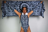 Model presenting a black and white tribal-patterned shawl from the Archaic Collection, paired with a coordinating bodysuit adorned with white fur, by Freedom Rave Wear.