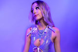 Woman in a shimmering bodysuit with cut-outs, under lavender light, looking contemplative
