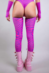 An up close photo of a woman's legs. She is wearing pink boots with pink and purple swirled leg sleeves that go up to her upper thigh. She is facing away from the camera.