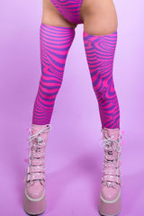 An up close photo of a woman's legs. She is wearing pink boots with pink and purple swirled leg sleeves that go up to her upper thigh.