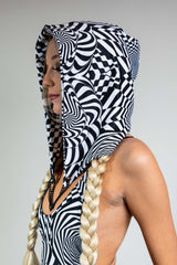 A woman wearing a black and white geometric printed hood and matching bodysuit. She is facing to the left.
