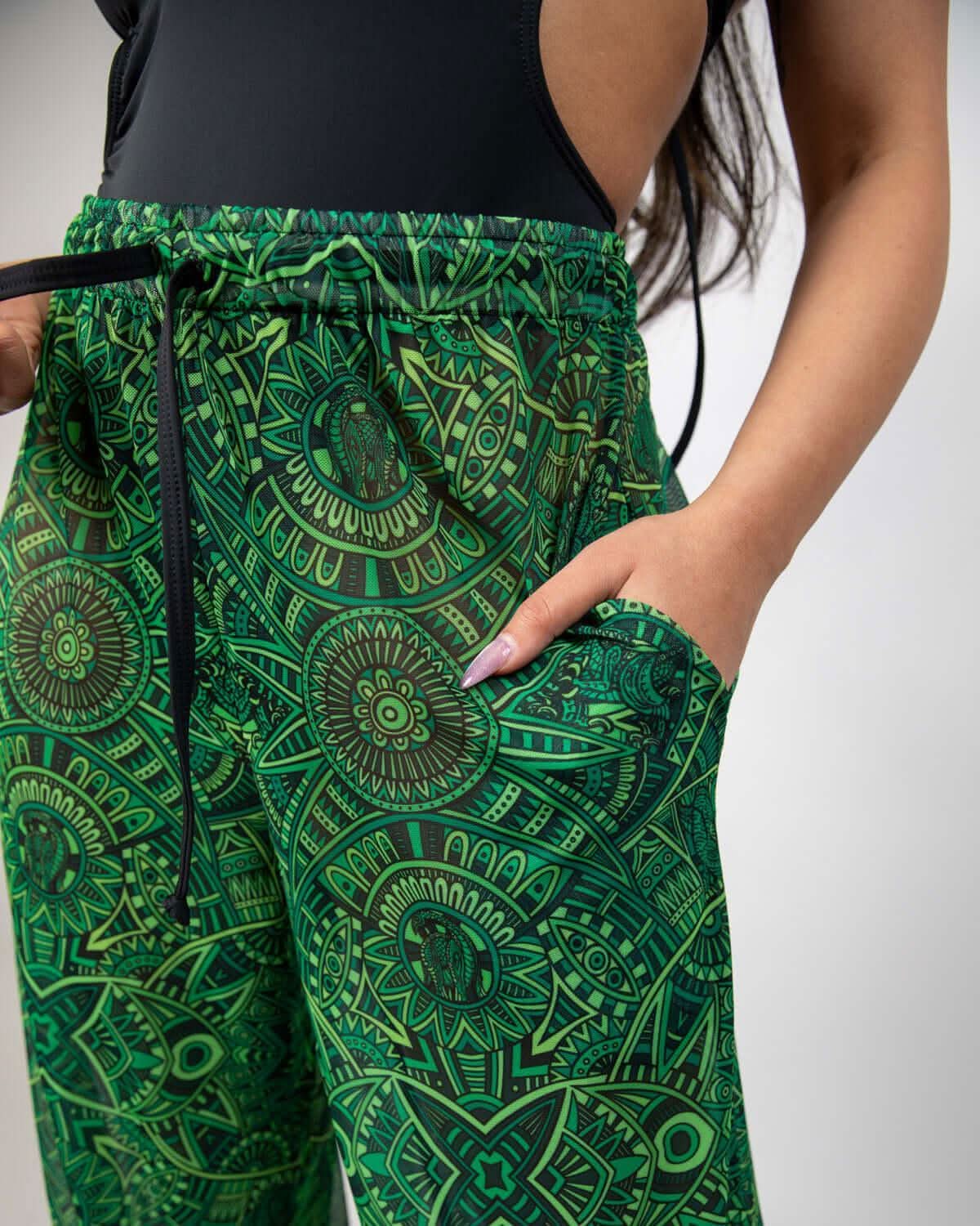 Dominion Mesh Lucy Pants in vibrant green with tribal print, showcasing pockets and a relaxed fit for rave bottoms.