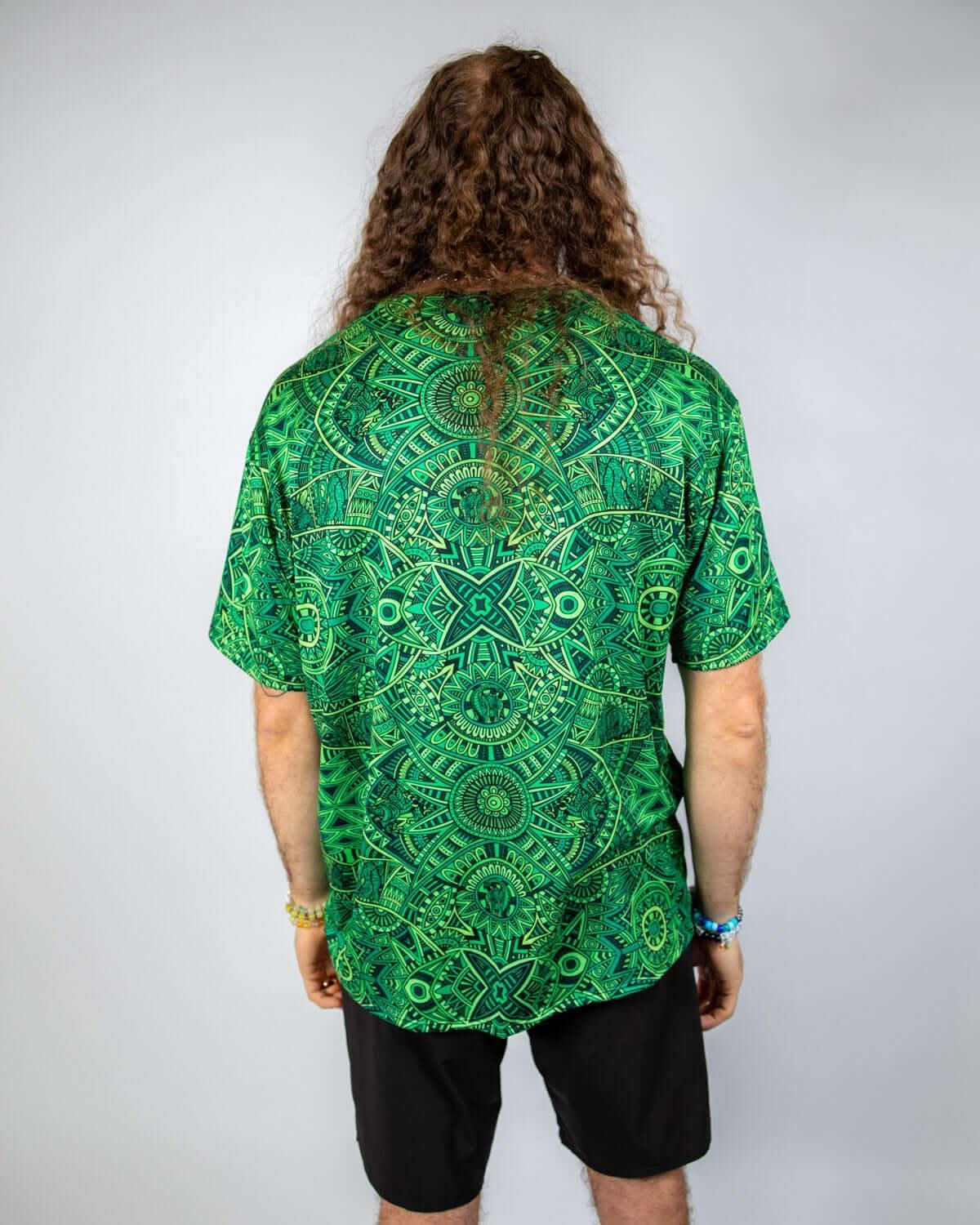 Back view of a man wearing a green psychedelic Rave T-Shirt with a bold pattern, showcasing relaxed oversized fit.