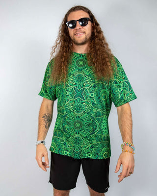 Man wearing a vibrant green oversized Rave T-Shirt with psychedelic patterns and sunglasses.