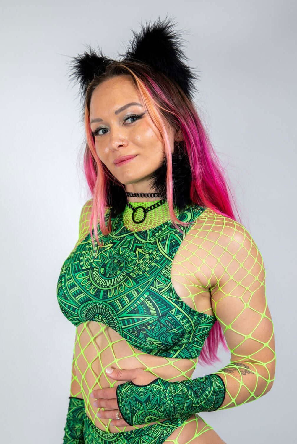 Model wearing a vibrant green rave top with underboob cut, fishnet details, and playful accessories, perfect for festivals.