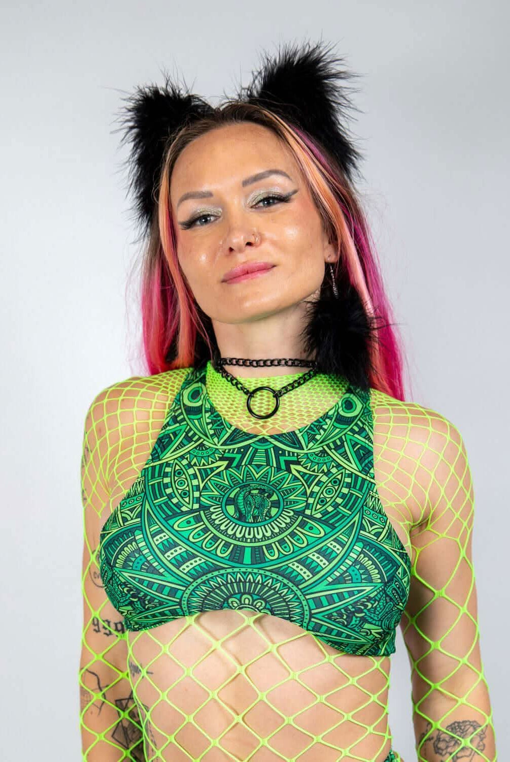 Model showcasing the Dominion Teaser Top with halter neckline, vibrant green print, perfect for rave fashion.