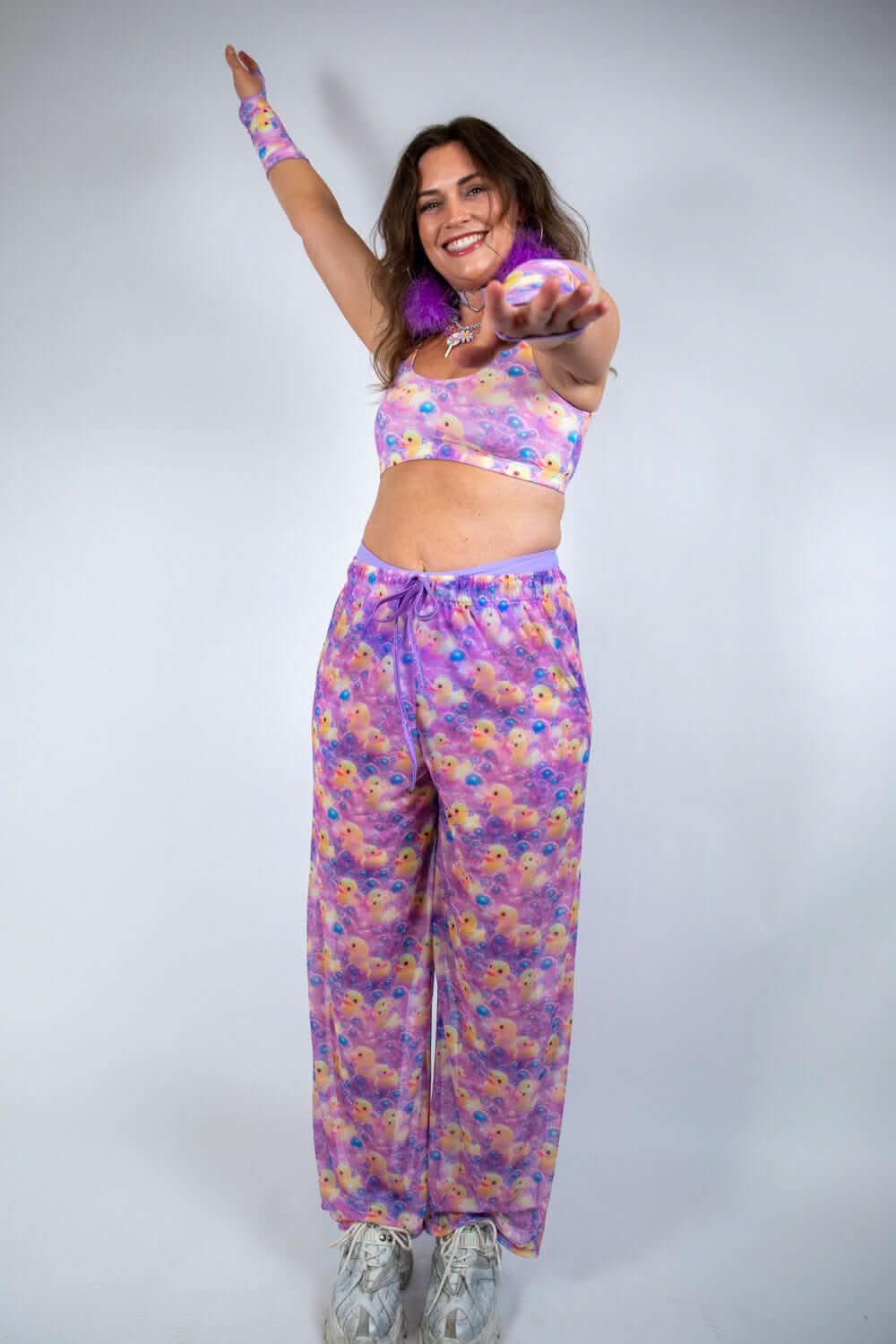 Model wearing Duckies Mesh Lucy Pants, vibrant purple, yellow, and pink rave outfits, ready to dance at a rave.