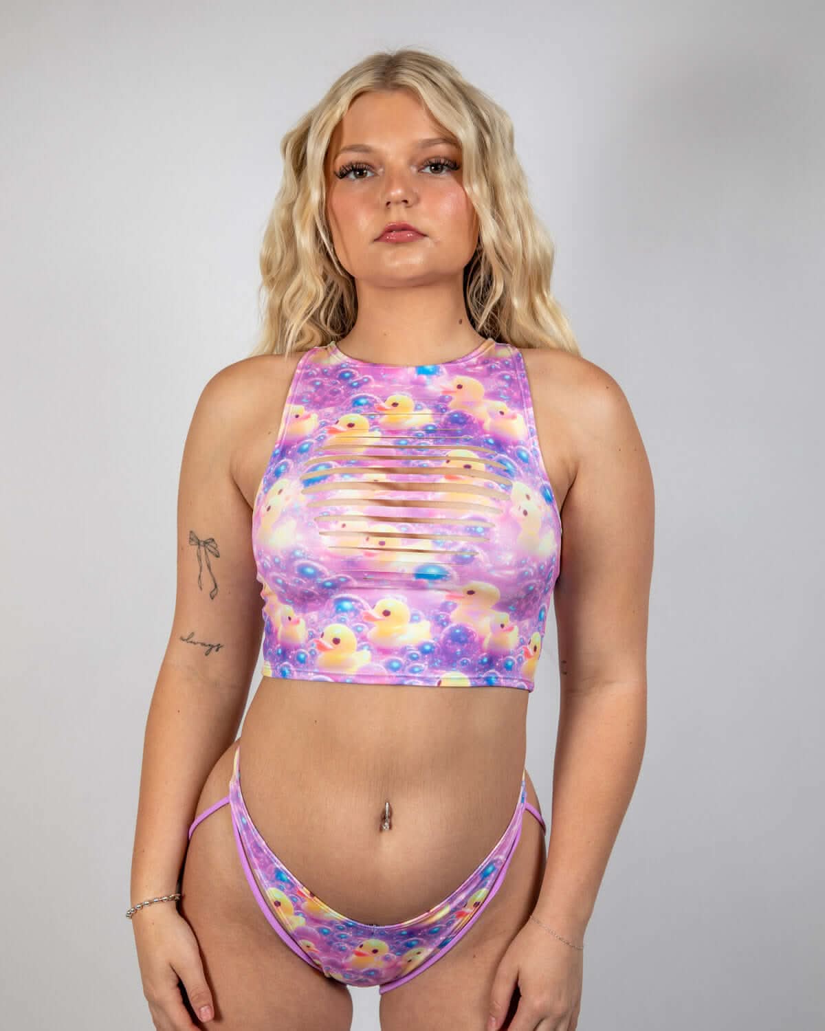 Duckies Slit Crop Top worn by model with playful purple, yellow, and pink design, perfect for rave outfits.