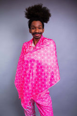 A man wearing a pink and white tank top with matching pants, wrapped in a matching pashmina.