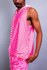 A man wearing a pink and white tank top with a hood and matching pants. He is facing to the left.