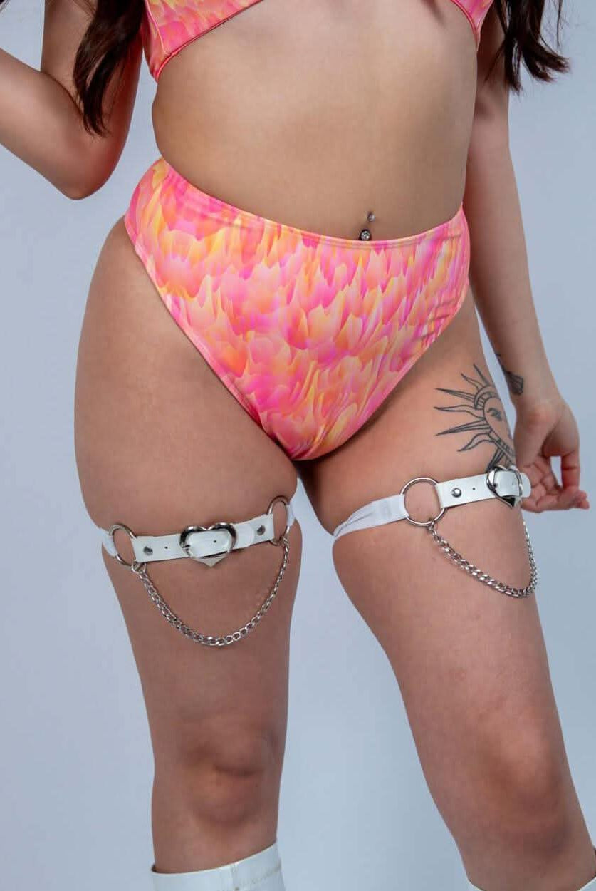 Model in a vibrant pink high-waisted thong with silver chain details, showcasing trendy rave outfit style.