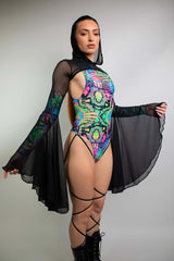 Model wearing Freedom Rave Wear bodysuit in vibrant psychedelic prints, with sheer long sleeves and dramatic flared cuffs, hood detail included.
