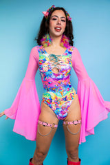 A woman wearing a rainbow bodysuit with whimsical characters printed on it, a lace up front detail, and flowy pink sleeves.