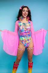 A woman wearing a rainbow bodysuit with whimsical characters printed on it, a lace up front detail, and flowy pink sleeves.