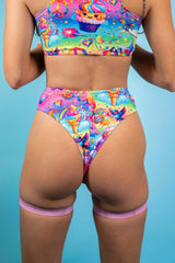 An up close photo of a woman wearing rainbow bikini bottoms with whimsical characters printed on them. She is facing away from the camera.
