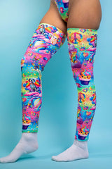 A girl's legs, wearing rainbow leg sleeves with whimsical characters on them. The sleeves go up to her mid thigh.