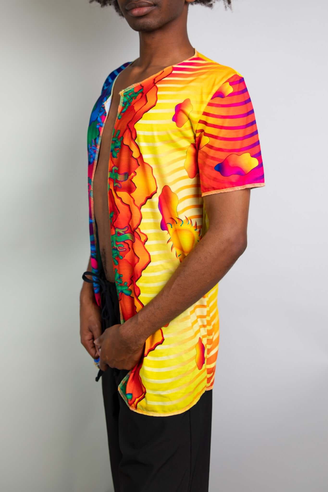 Side view of a man wearing a Freedom Rave Wear open tee featuring vibrant sun and cloud prints, designed for standout rave fashion.
