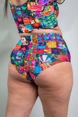 A woman wearing rainbow patchwork bikini bottoms and a matching crop top. She is facing away from the camera.