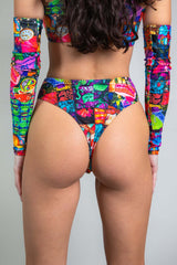 An up close photo of a girl wearing a high waisted rainbow patchwork bikini bottom with a matching crop top. She is facing away from the camera.