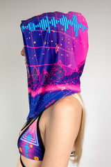 A woman wearing a neon pink and purple printed rave bikini with a matching hood. She is facing to the left.