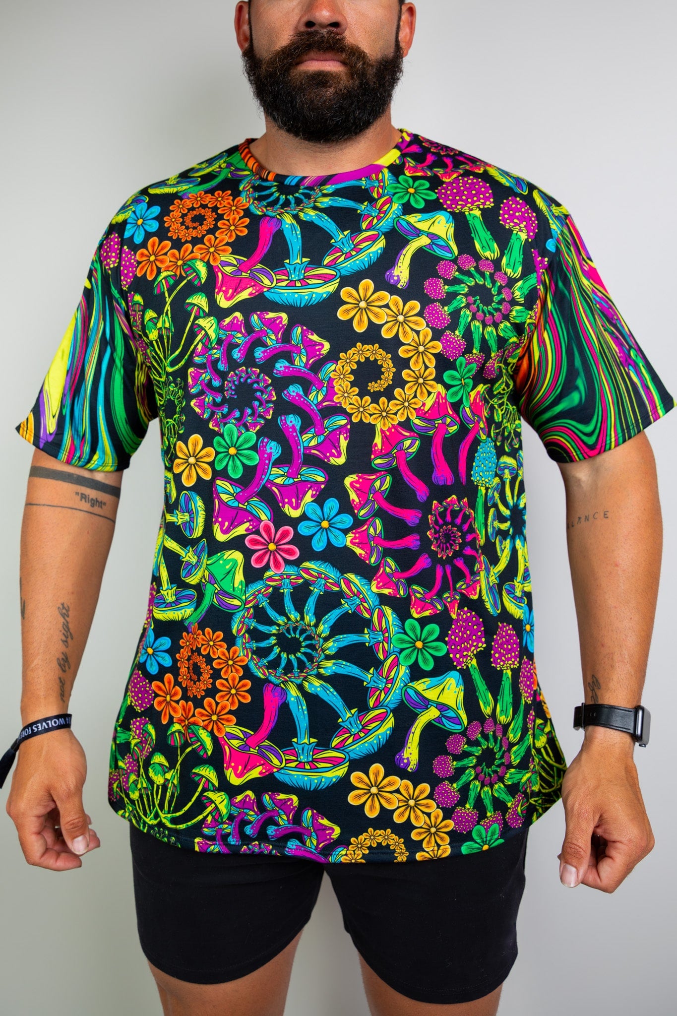  Model in a vibrant, psychedelic floral t-shirt with bold patterns, perfect for raves. Freedom Rave Wear offers unique festival fashion.
