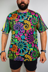  Model in a vibrant, psychedelic floral t-shirt with bold patterns, perfect for raves. Freedom Rave Wear offers unique festival fashion.