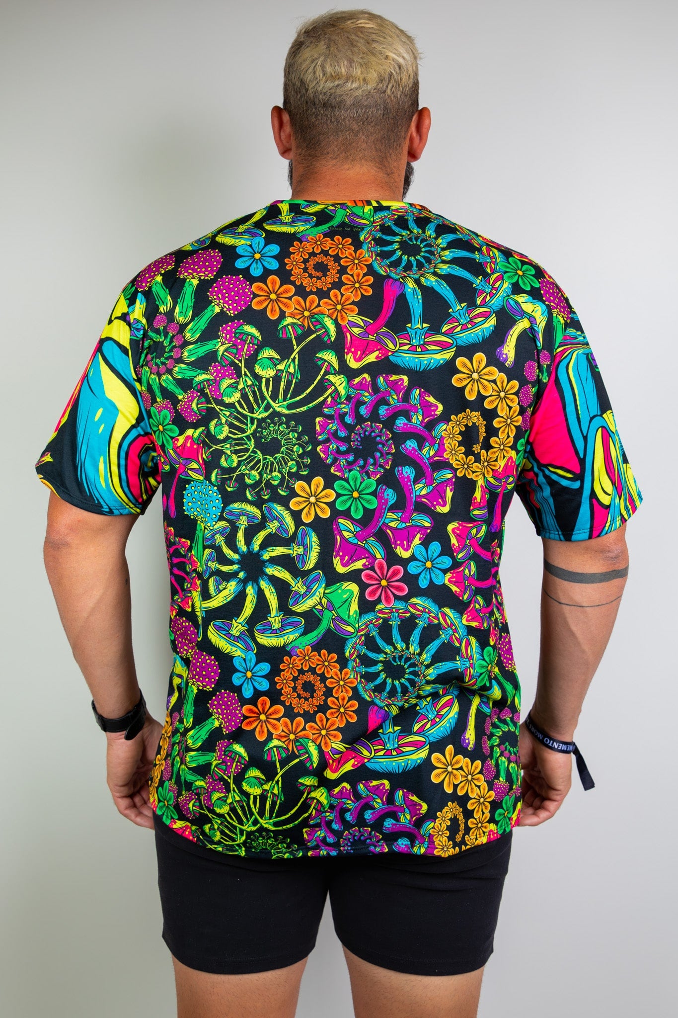  Model showing back view of a vibrant, psychedelic floral t-shirt with bold patterns, ideal for raves. Freedom Rave Wear offers unique fashion.
