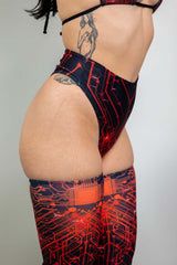 Side profile of a woman in a black and red Freedom Rave Wear high-waisted bottom with a vibrant circuit design, paired with complementary thigh-high leggings