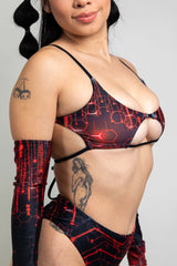 Woman in a black and red Freedom Rave Wear rave top with high-waisted bottoms, showcasing intricate circuit designs and cut-out details, paired with matching sleeves
