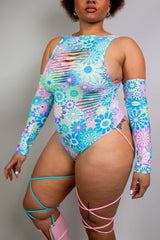 Model wearing Freedom Rave Wear floral bodysuit featuring pastel hues, vibrant cut-outs, and crisscross leg straps.