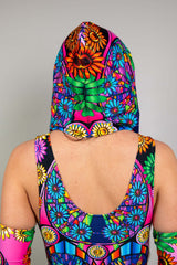 A photo of a girl looking away from the camera wearing a rainbow stained glass printed hood and a matching bodysuit.
