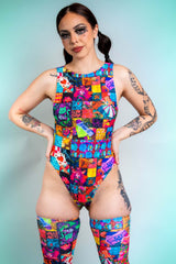 A girl with swirly black eye makeup poses in a rainbow patchwork bodysuit.