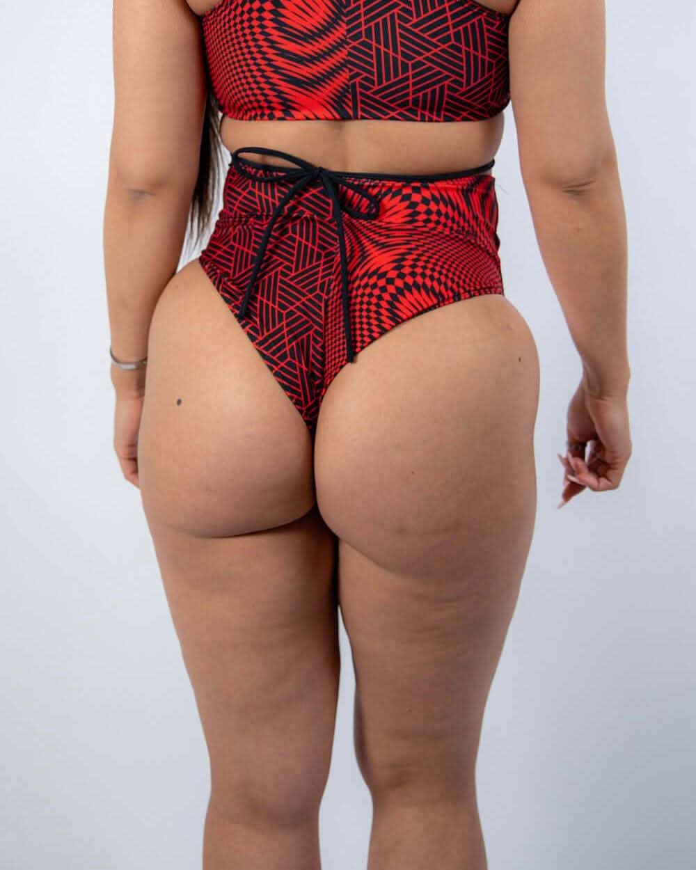 Back view of Amplitude High Waisted Bikini Bottoms featuring a red and black abstract design, perfect for rave outfits.