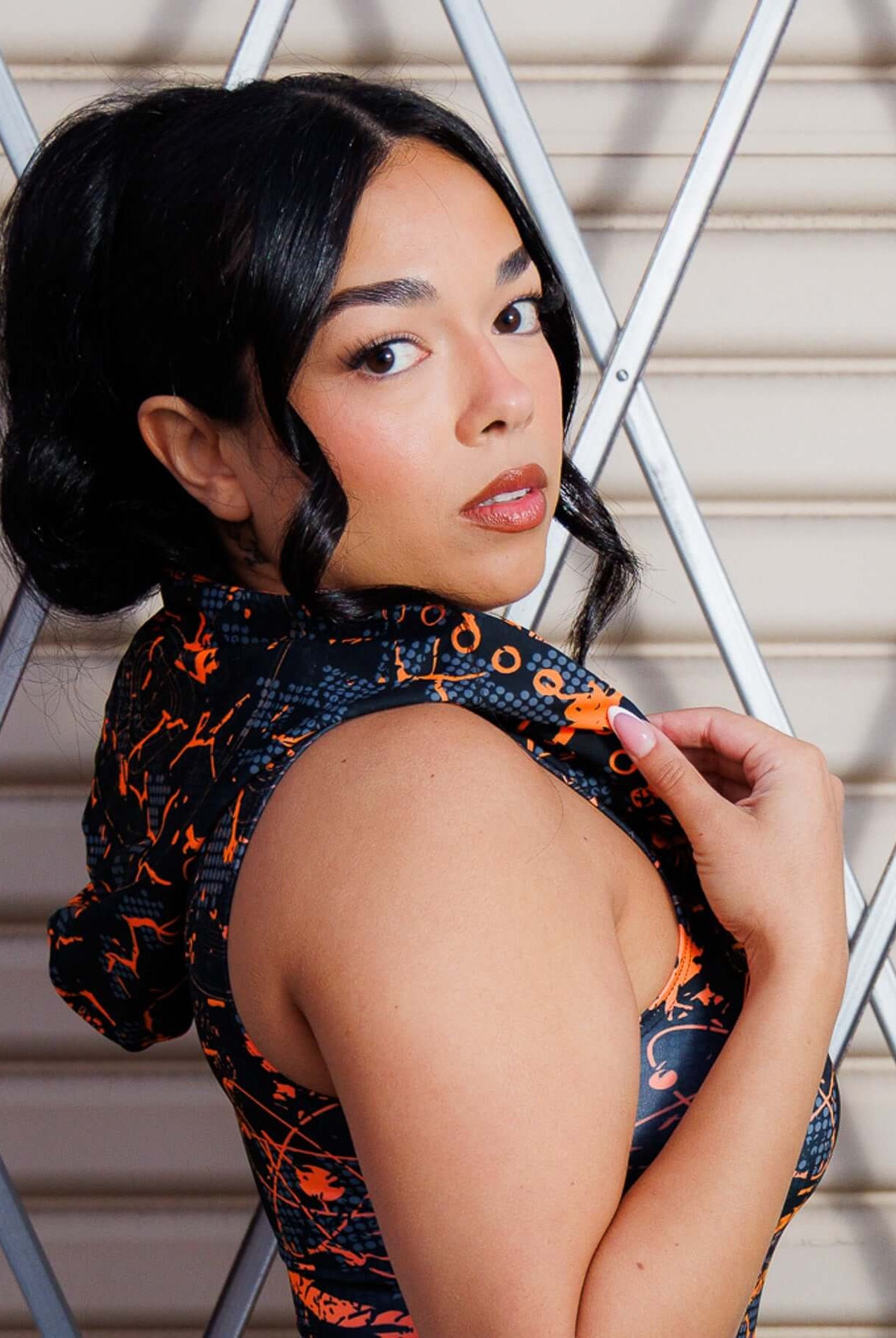 Model wearing Atomic Assassin Hood in orange and black design.