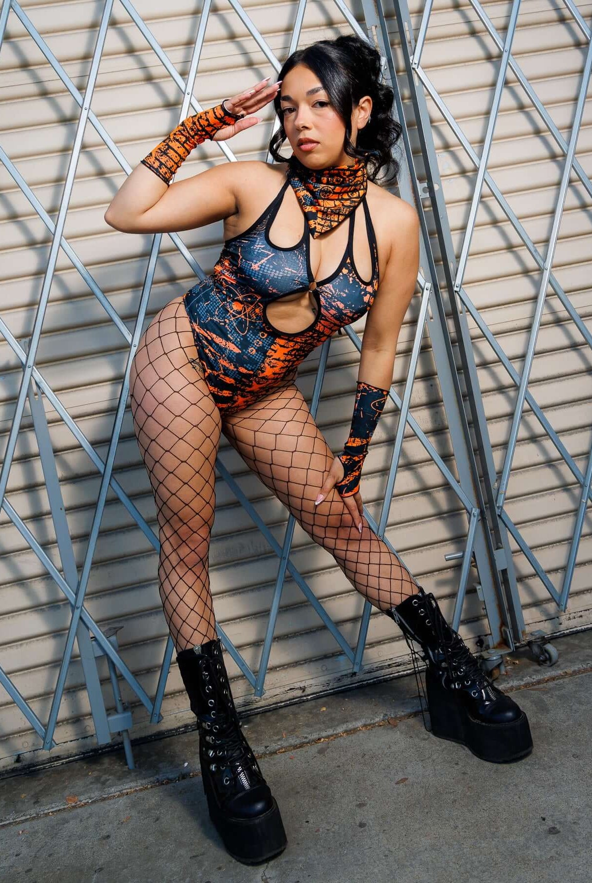 Model wearing the Atomic Bandana in festival attire with orange and black tones, showcasing its edgy dystopian style against a metal backdrop.