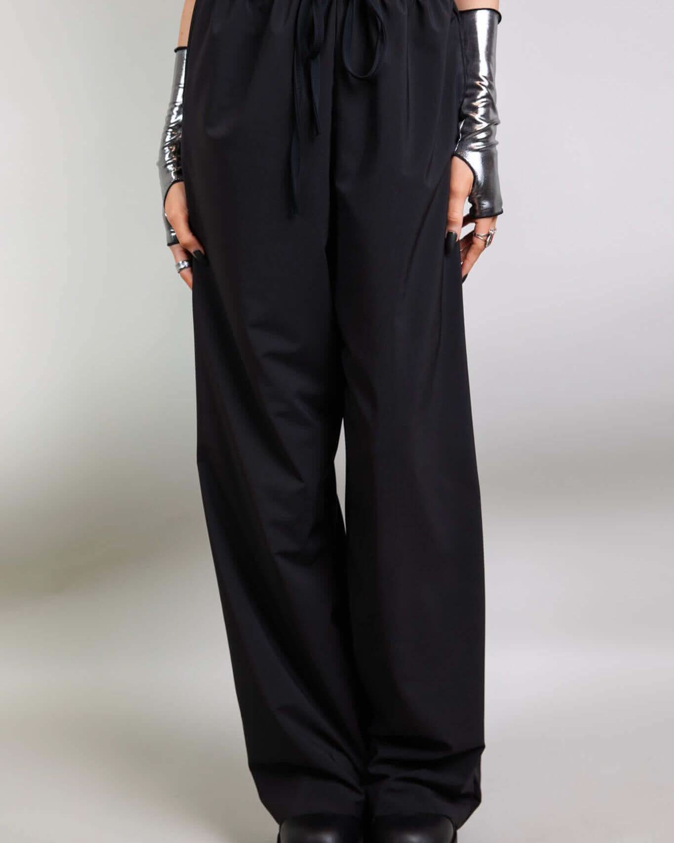 Model wearing Basic Black Lucy Pants with elastic waistband and wide leg design, perfect for rave outfits.