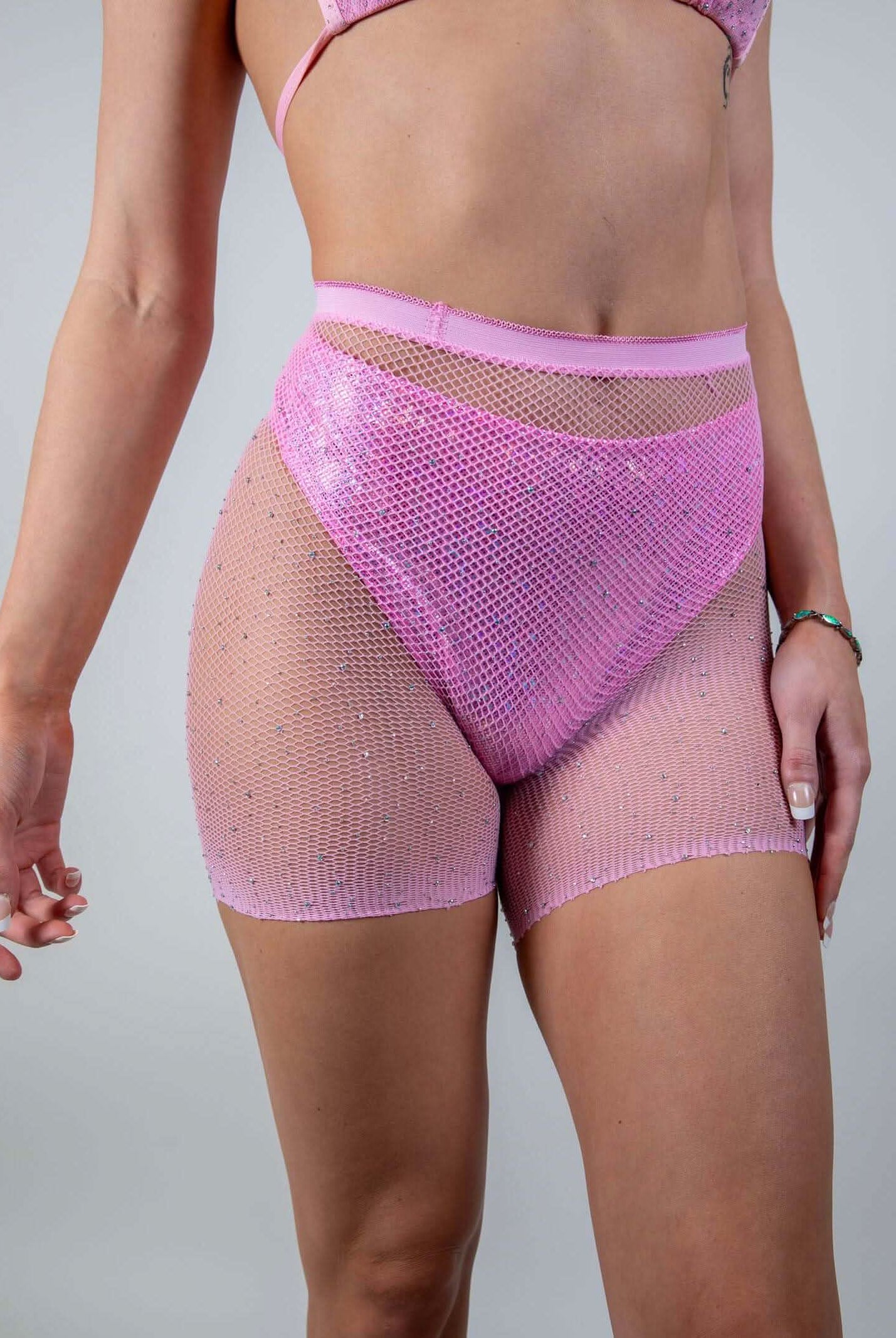 Angled front view of the Bikini Babe Rhinestone 2 Piece Fishnet Set in pink, emphasizing its vibrant color and sparkling accents.