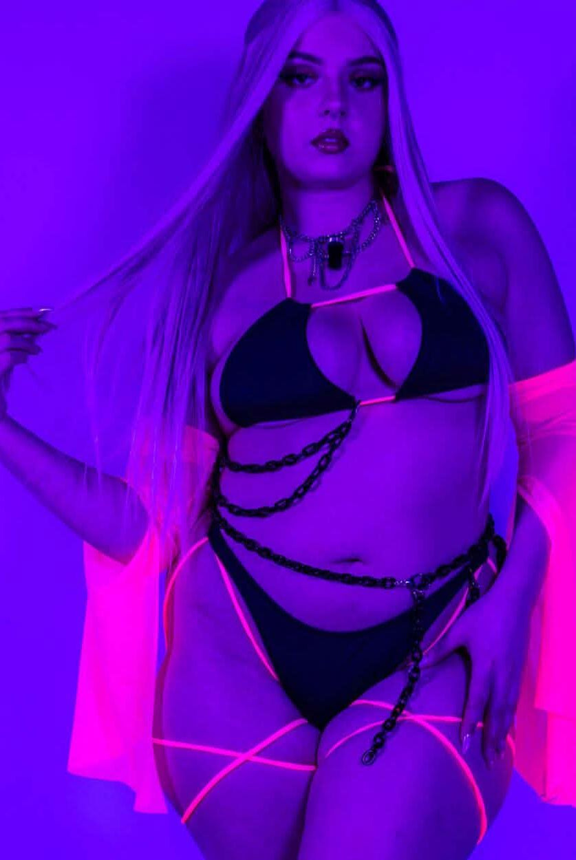 Neon-lit pose of the Black and Hot Pink Strappy Bikini Top, glowing under blacklight for a bold rave look.