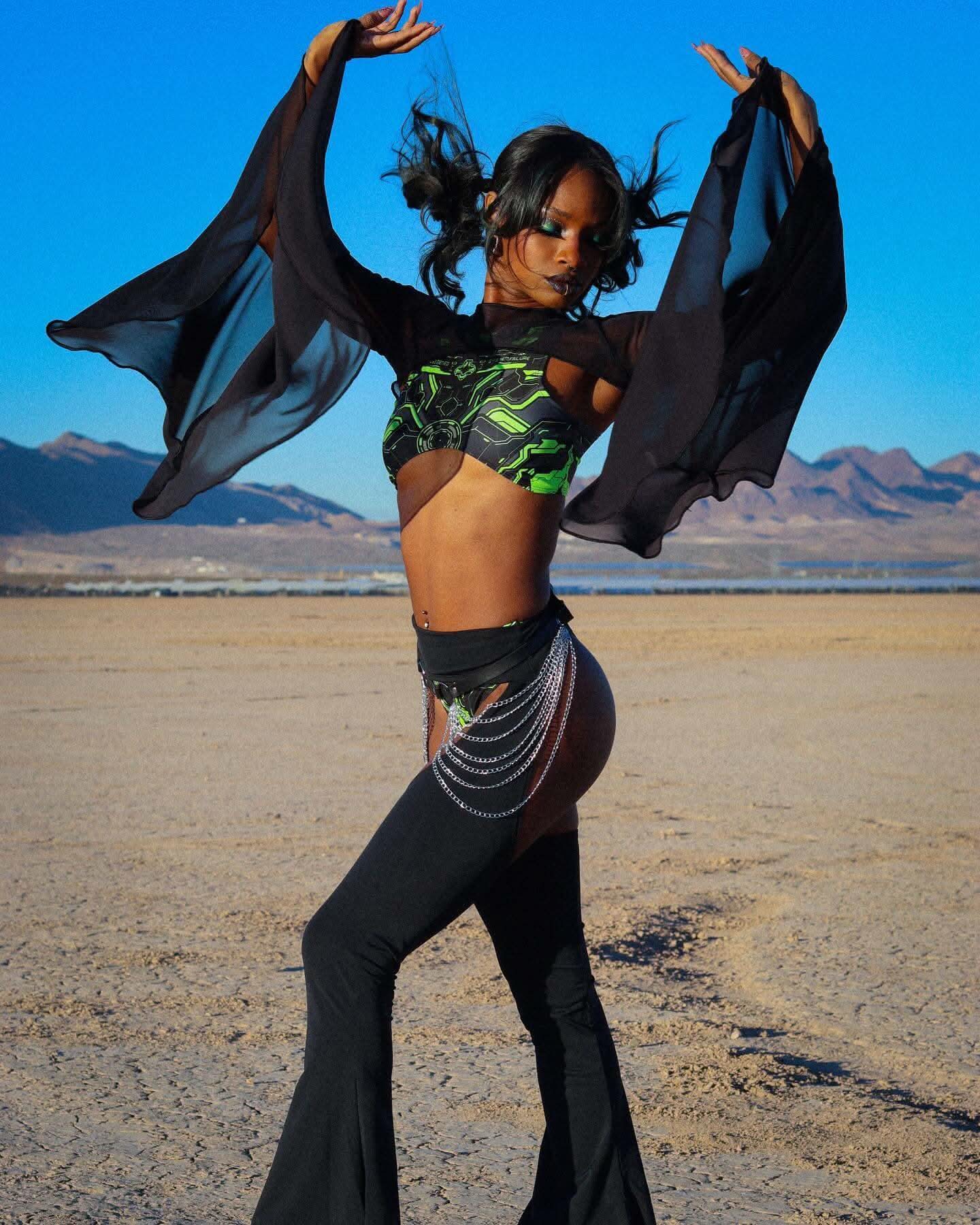 Model showcasing black mesh bell sleeves with rave outfit in a desert landscape, capturing an ethereal vibe.