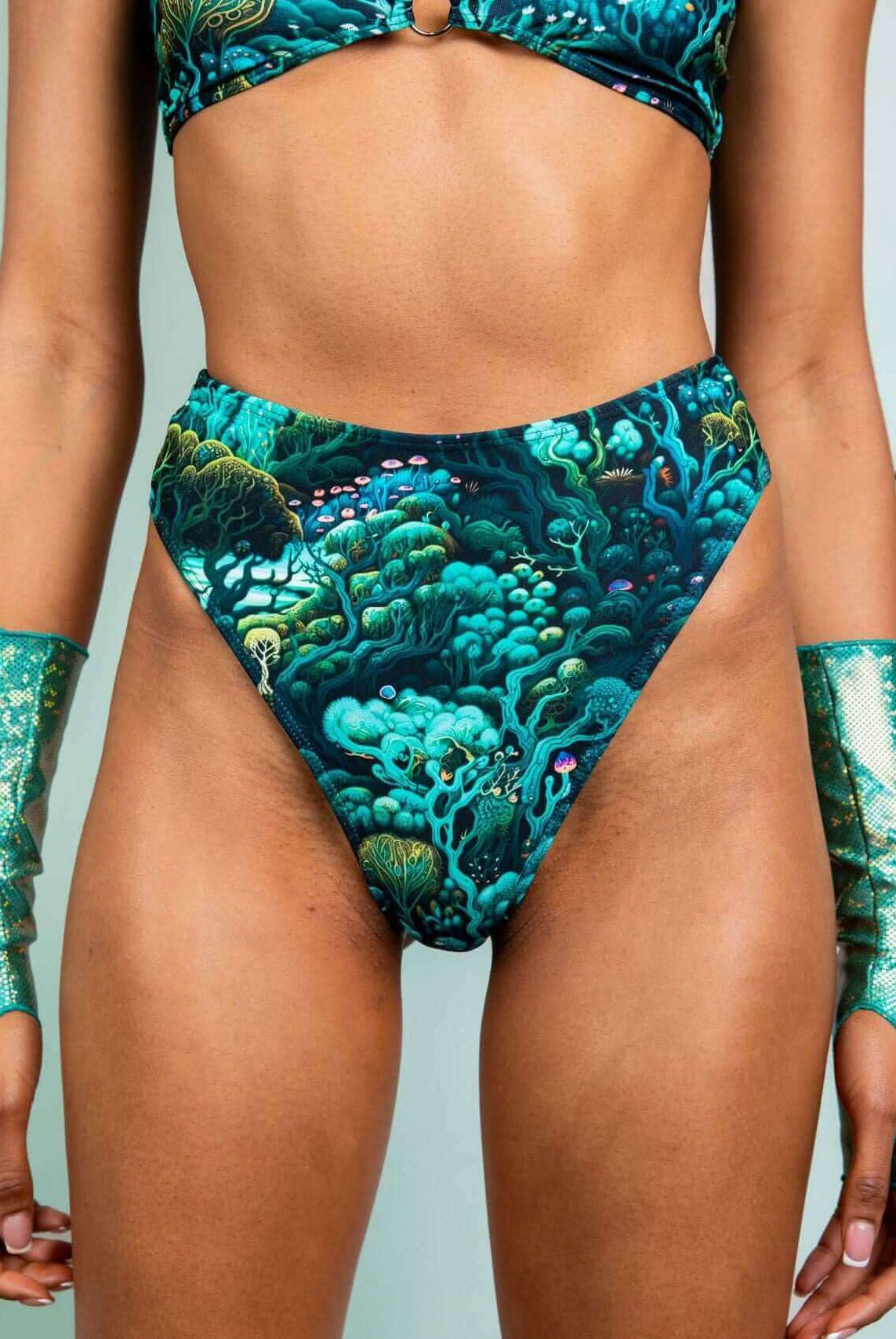 Model wearing Faewood High Waisted Thong with forest print, styled with matching glitter sleeves for a rave-ready look.