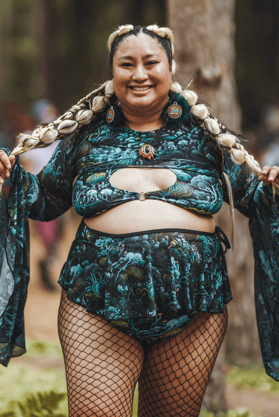 Smiling person in Faewood Keyhole Top and matching bottoms, showcasing rave outfit in a forest setting.