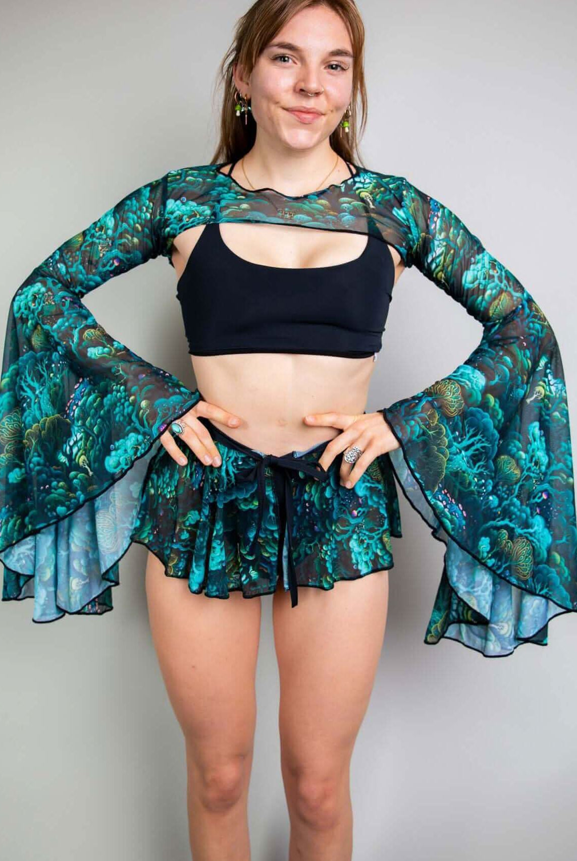 Model showcasing Faewood Mesh Bell Sleeves paired with a black crop top and matching shorts for a rave outfit.