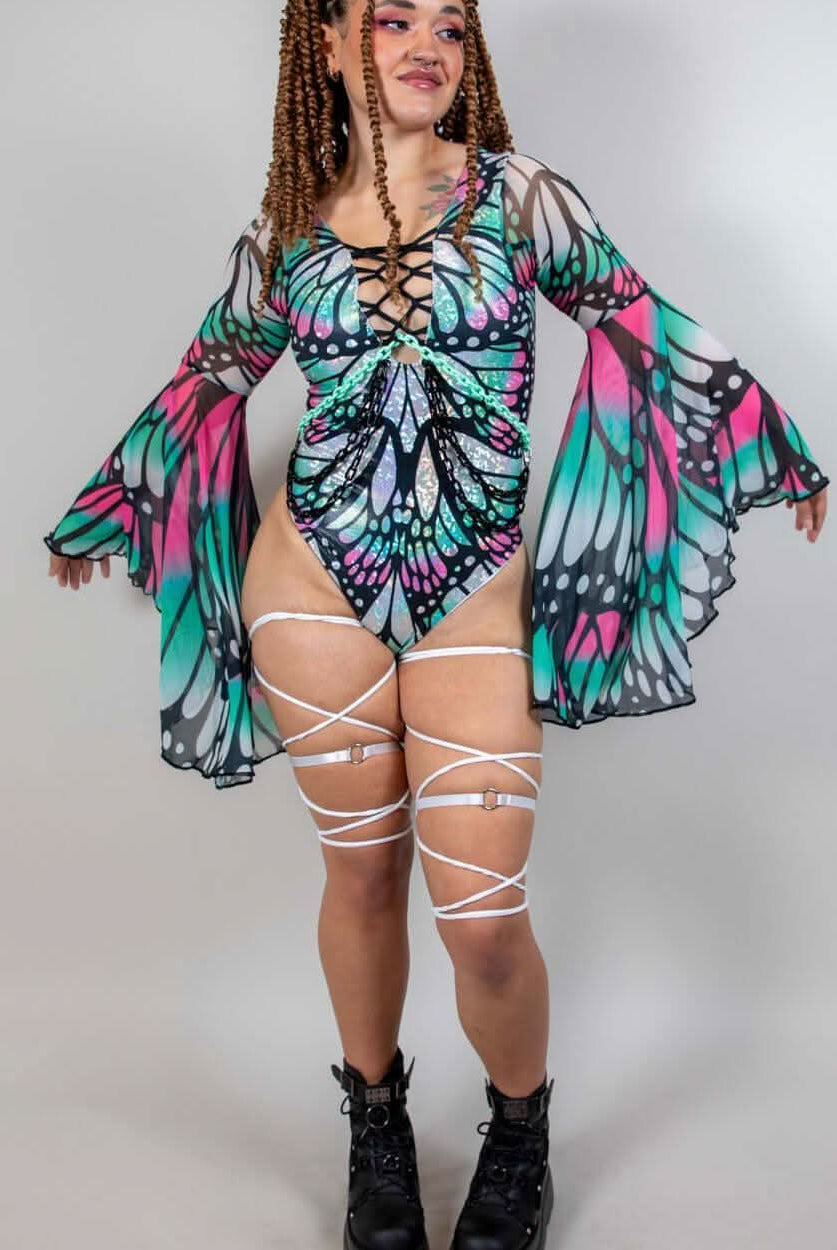 Model in a Flutter Goddess bodysuit with butterfly pattern, lace-up detailing, and flowy bell sleeves, showcasing rave outfits.