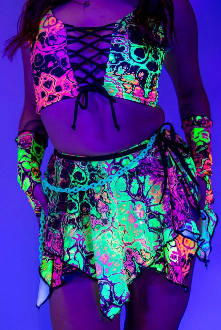 Model wearing a vibrant neon Intensity Fairy Skirt and matching top, perfect for rave outfits in blacklight.