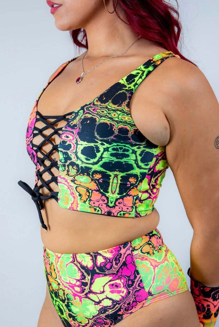 Vibrant model wearing Intensity Lace Up Top with lace front, showcasing colorful UV reactive fabric, ideal for rave outfits.