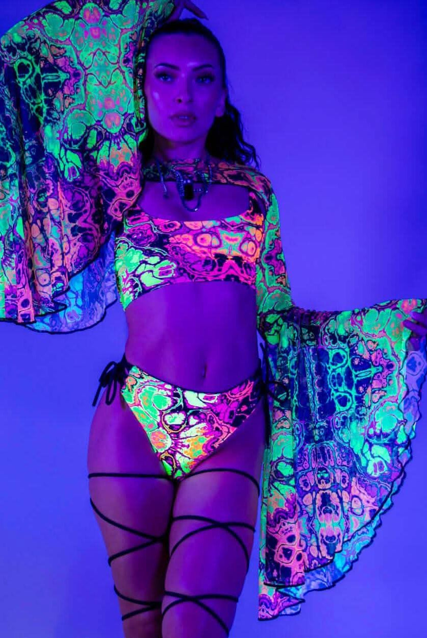 Model showcasing vibrant Intensity Mesh Bell Sleeves with UV reactive patterns, perfect for rave outfits.