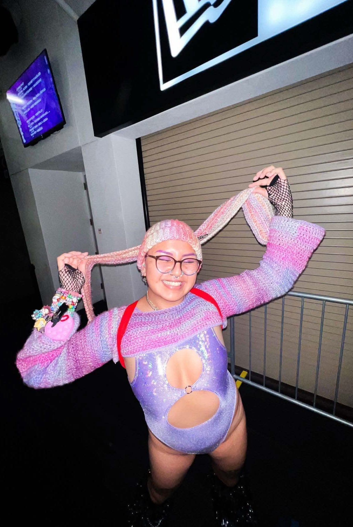 Trendy rave outfit featuring a Lavender Holo Keyhole Bodysuit with colorful accessories and playful hairstyle.