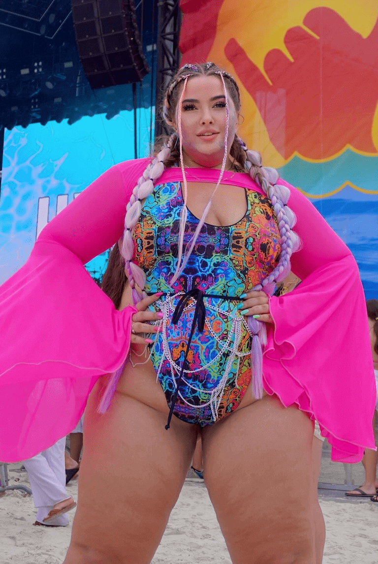 Comfy plus-size rave outfit featuring a psychedelic rainbow one-piece swimsuit at a festival.